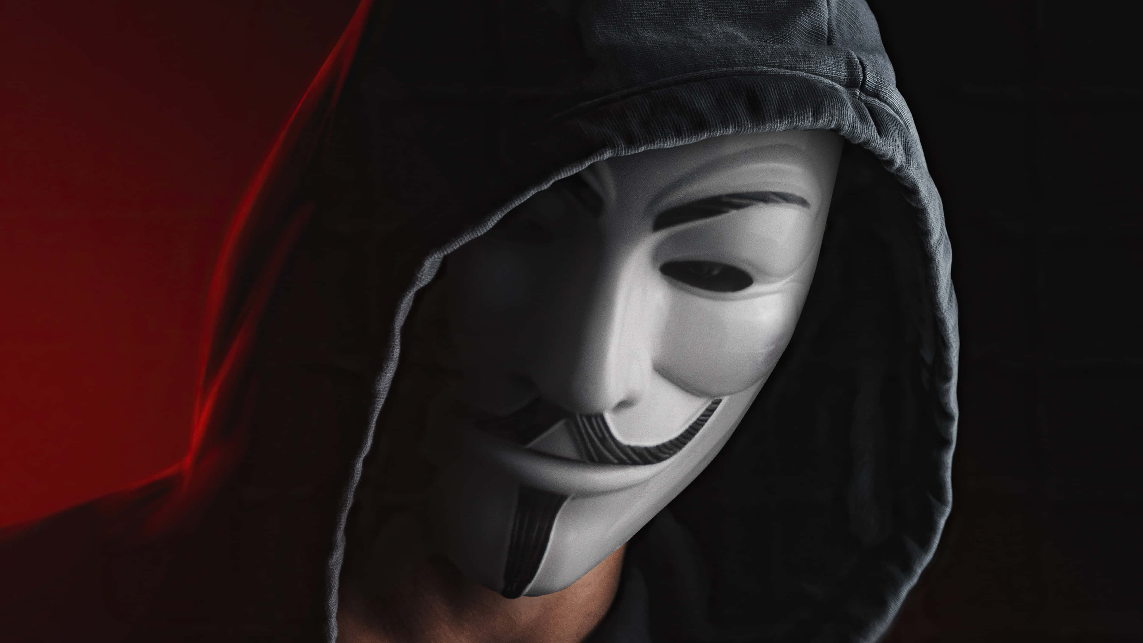 Hoodie 桌布 壁紙 — 一個穿著深色連帽衫的人，在鮮明的紅黑背景下戴著白色蓋伊·福克斯面具。