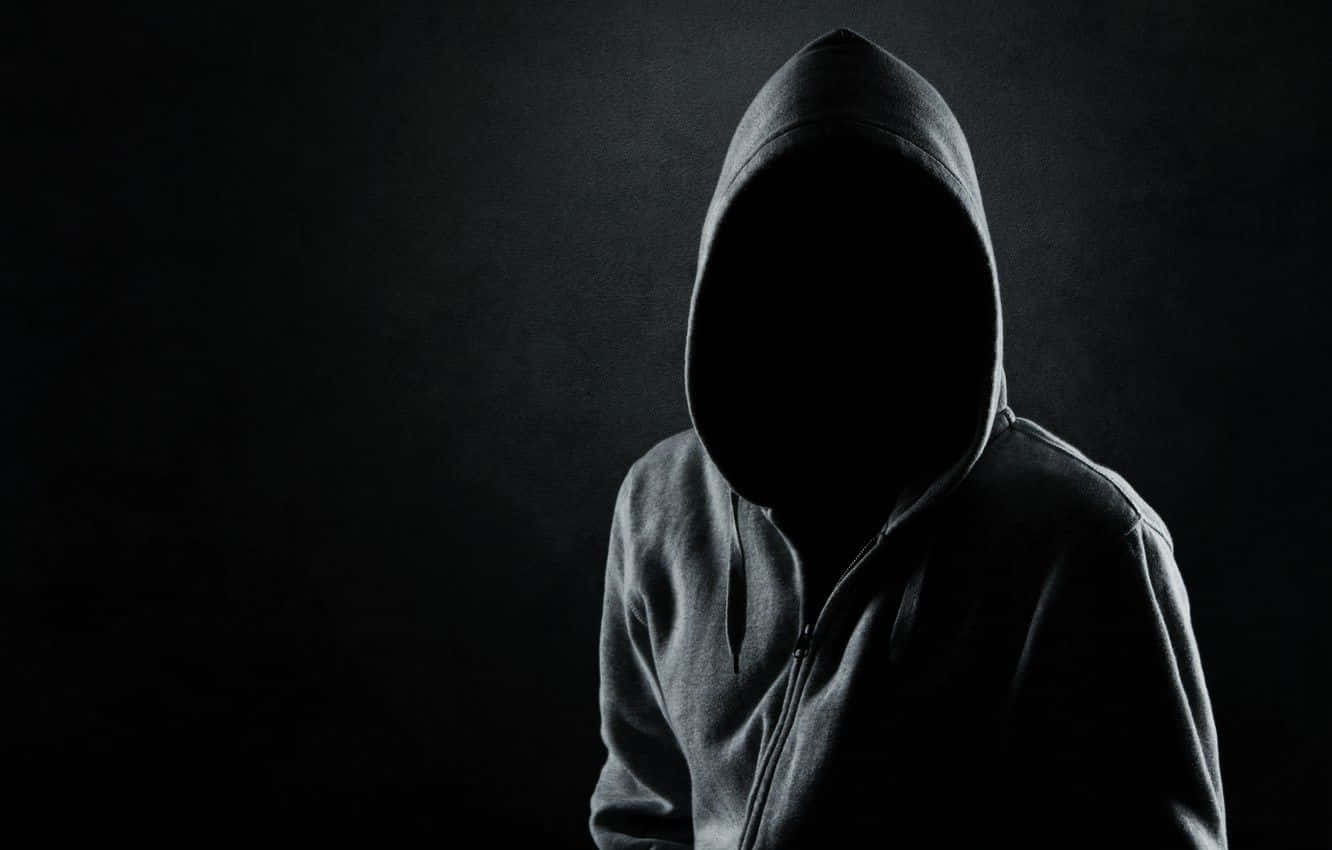 Mysterious 桌布 壁紙 — 一個穿著深色連帽衫的神秘人物站在黑色背景前，臉部被深邃的剪影遮蓋。