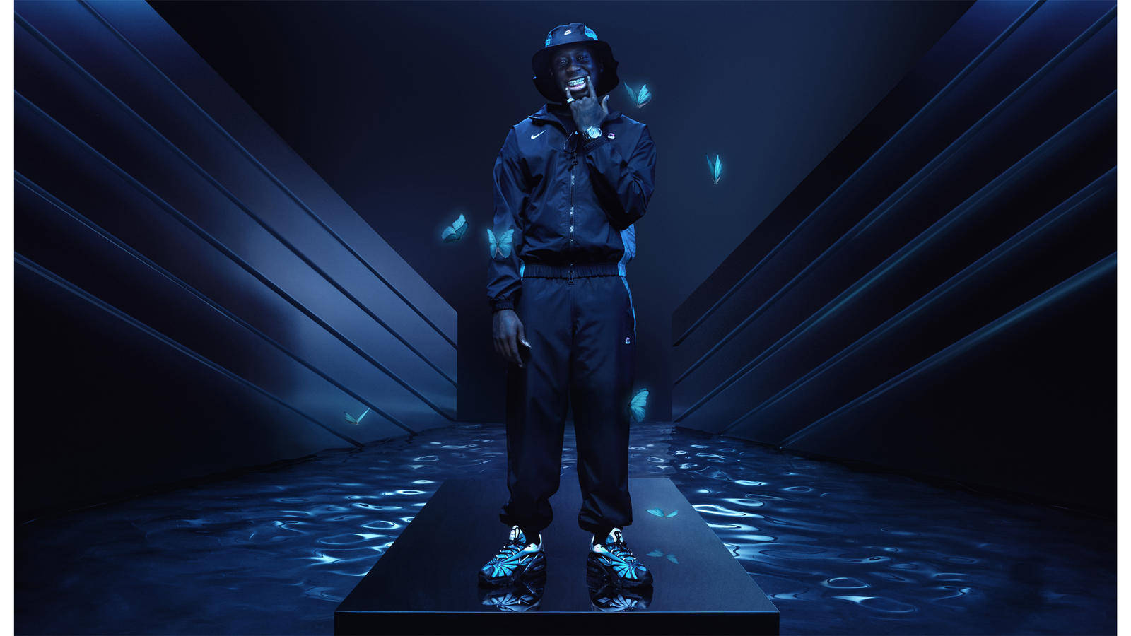 Skepta 桌布 壁紙 — 一個穿著深色運動服的人站在未來感藍色發光隧道中央，周圍有發光蝴蝶飄浮。