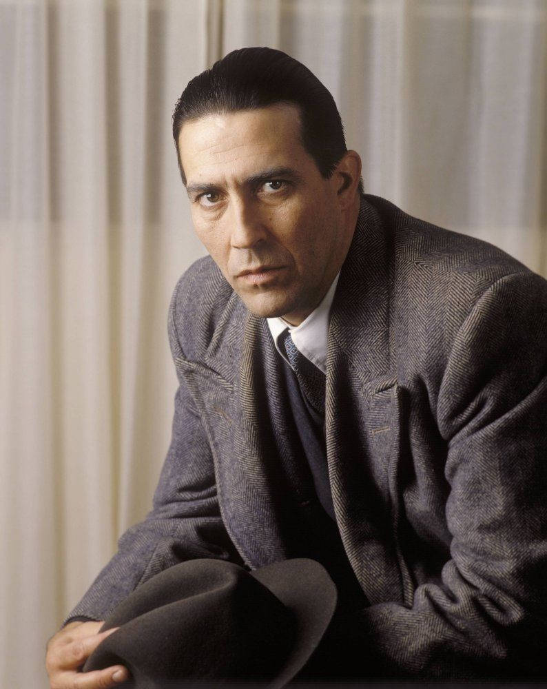 actor 桌布 壁紙 — 一個穿著灰色人字紋西裝的男人，在柔軟的窗簾背景下，拿著帽子，專注地凝視著相機。