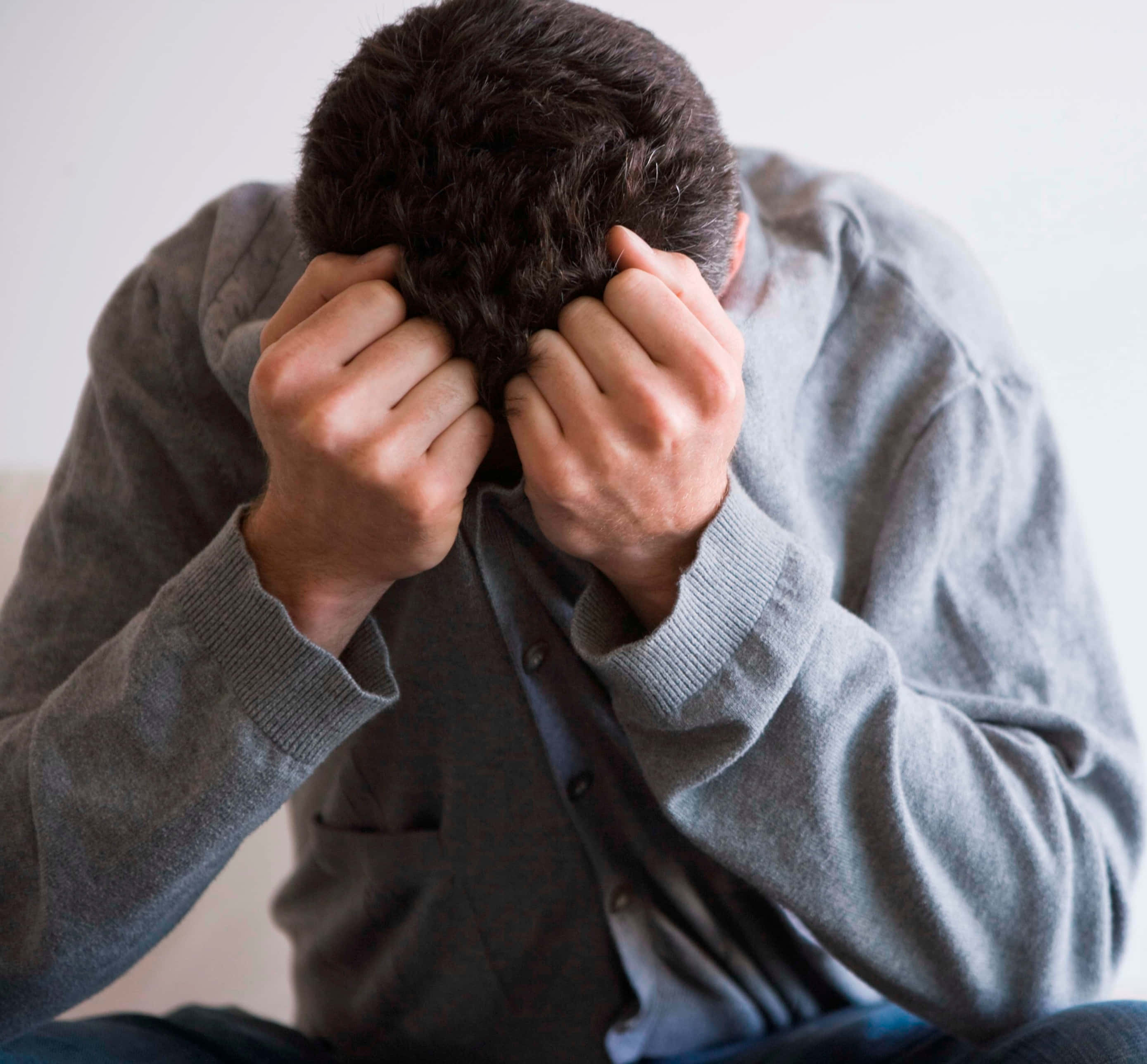 Annoyed 桌布 壁紙 — 一個穿著灰色毛衣的人，在純白色背景前痛苦地抓著頭髮。
