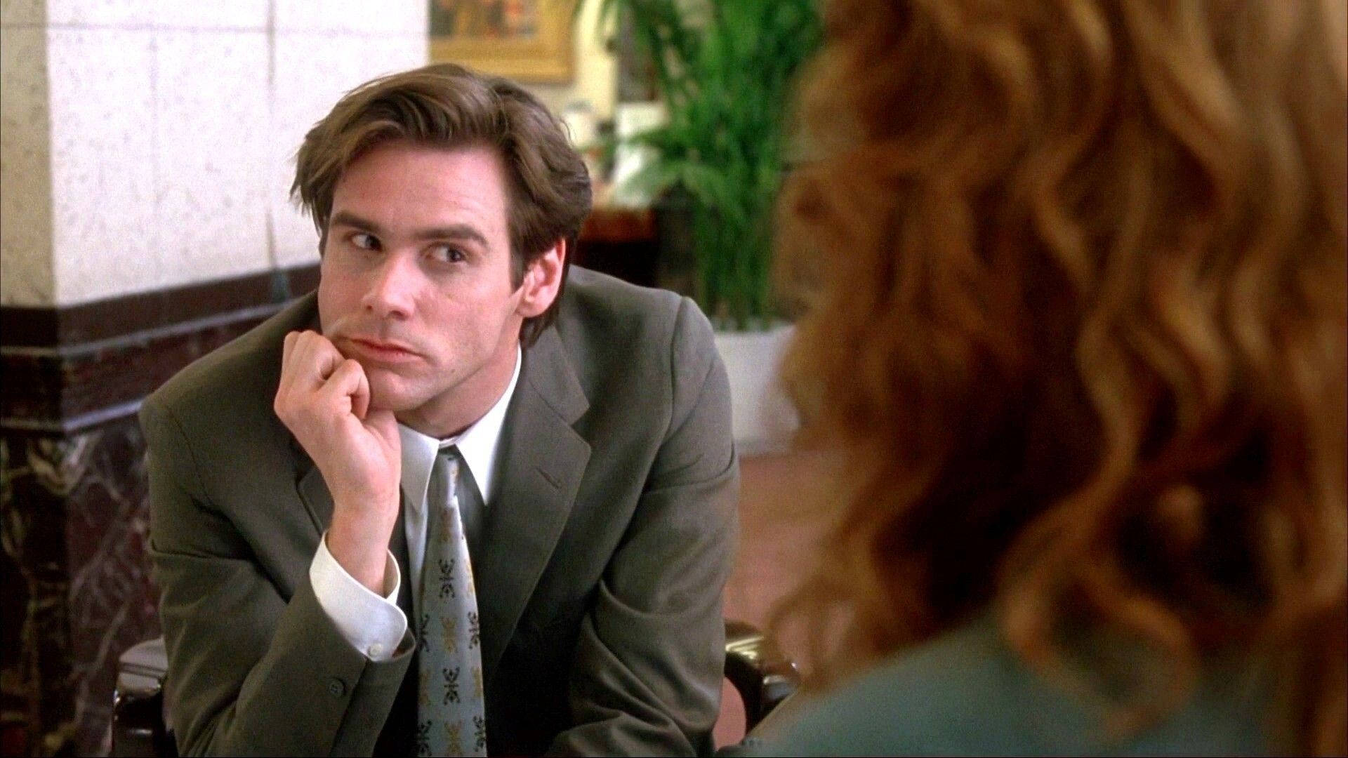 Jim Carrey 桌布 壁紙 — 一個穿著灰色西裝的男人托著下巴，專注地看著對面一個捲曲紅髮的女人。