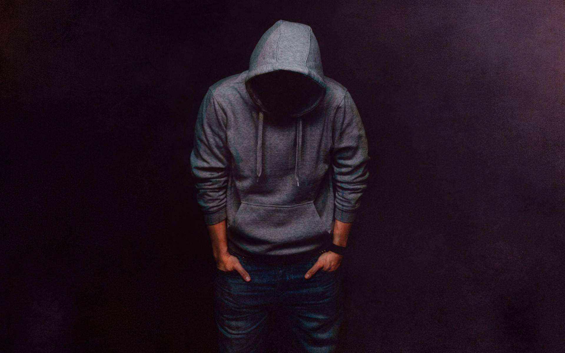 Denim 桌布 壁紙 — 一個穿著灰色連帽衫、低著頭的人站在昏暗光線中，背景漆黑。