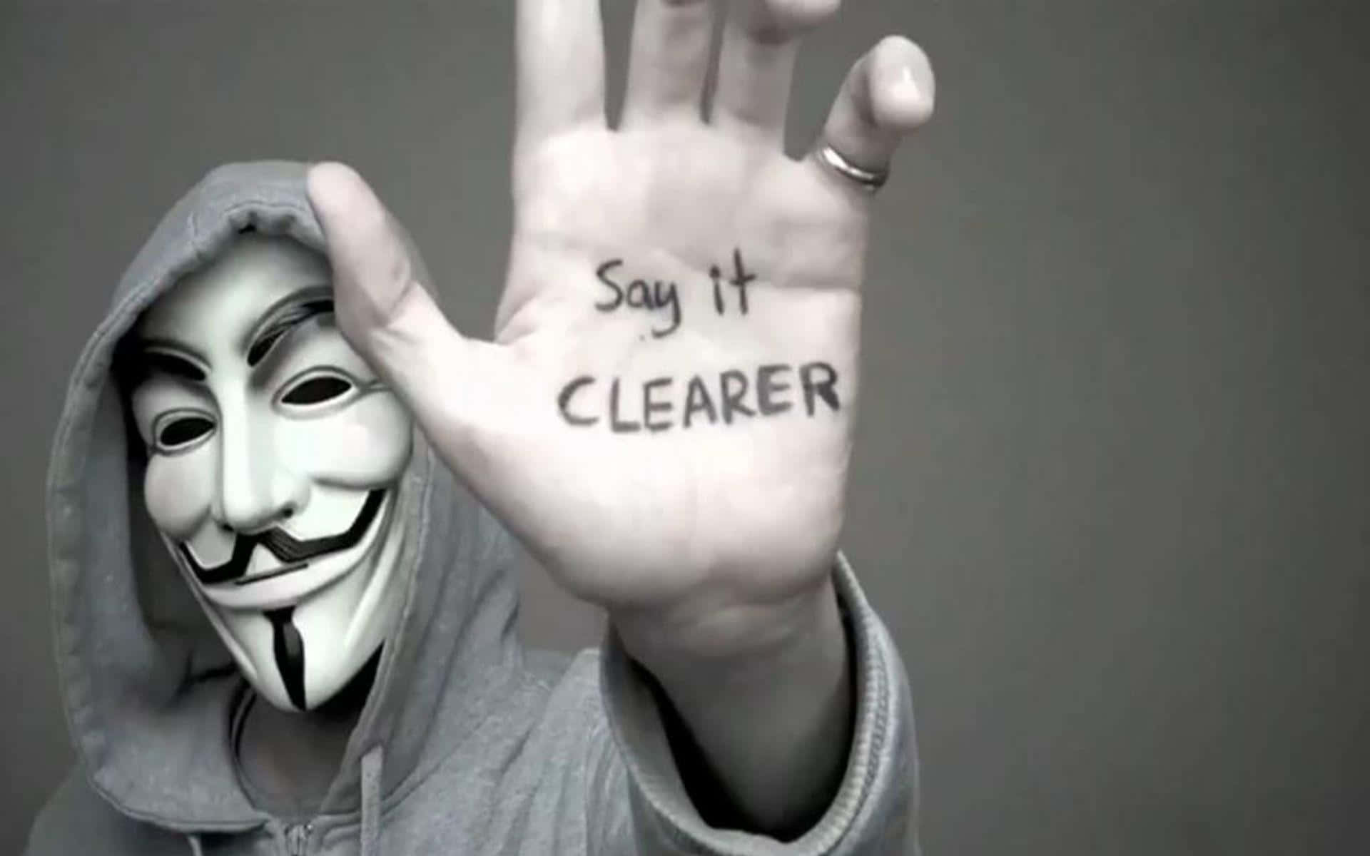 戴著蓋伊·福克斯面具的人舉起寫有Say it CLEARER訊息的手。 — 匿名 GIF 壁紙