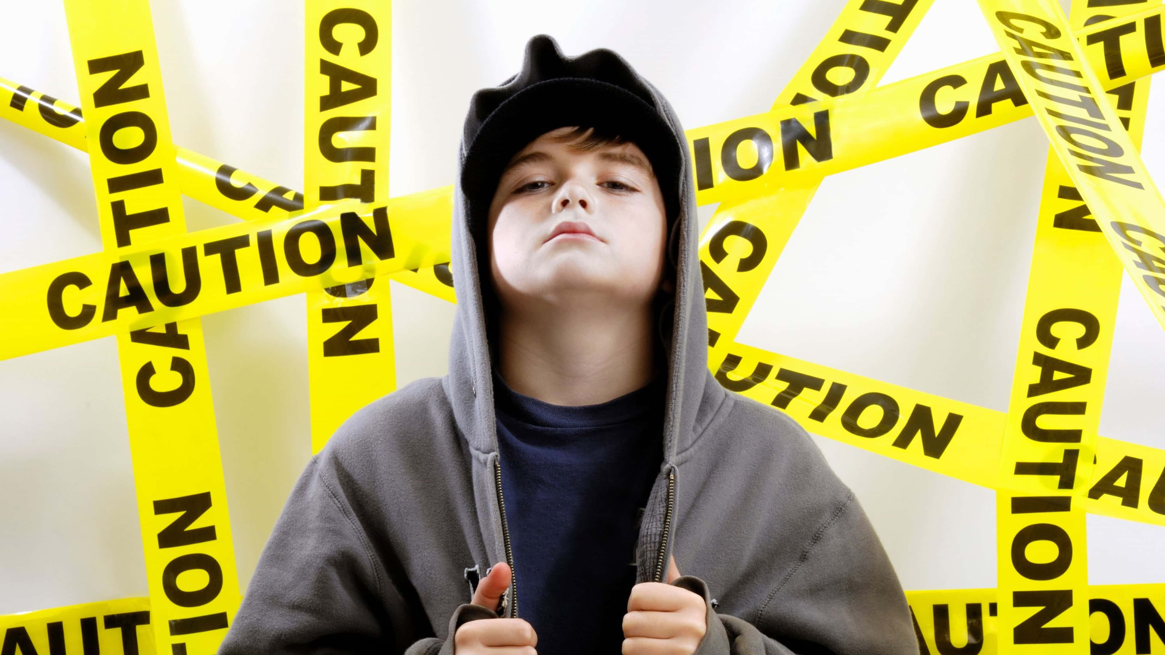 boys attitude 桌布 壁紙 — 一個穿著灰色連帽衫的小男孩挑釁地站在交錯的黃色警示帶中。