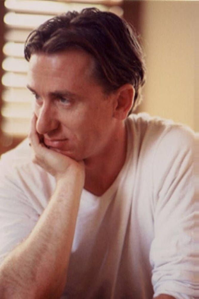 in love 桌布 壁紙 — 一個穿著白色T恤的男人，托著下巴，若有所思地望向旁邊，光線柔和溫暖。