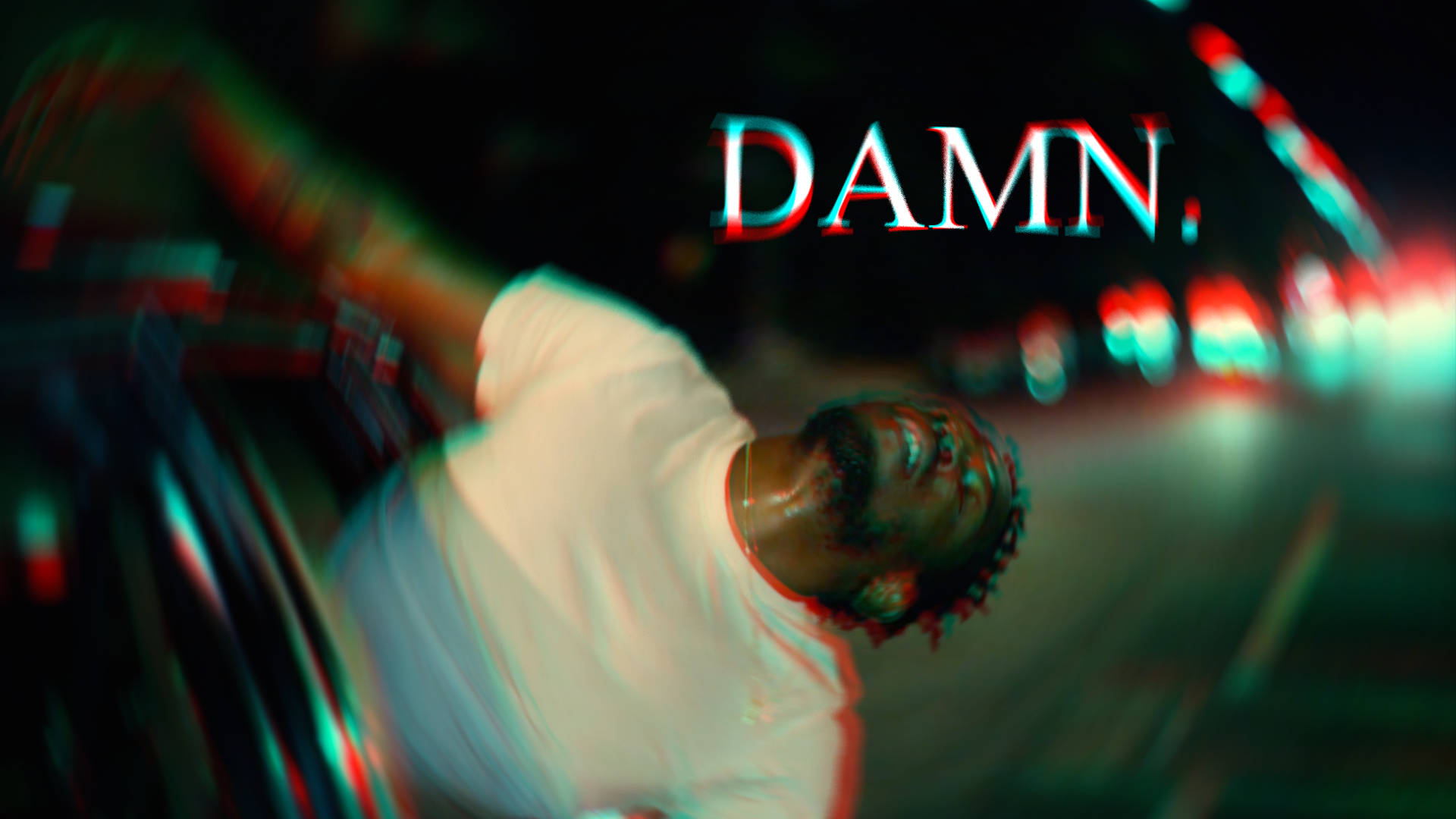 Kendrick 桌布 壁紙 — 一個穿著白色T恤的男人向後靠在模糊的夜晚街道上，閃爍著紅色和青綠色的光芒，他上方有故障風格的文字DAMN。