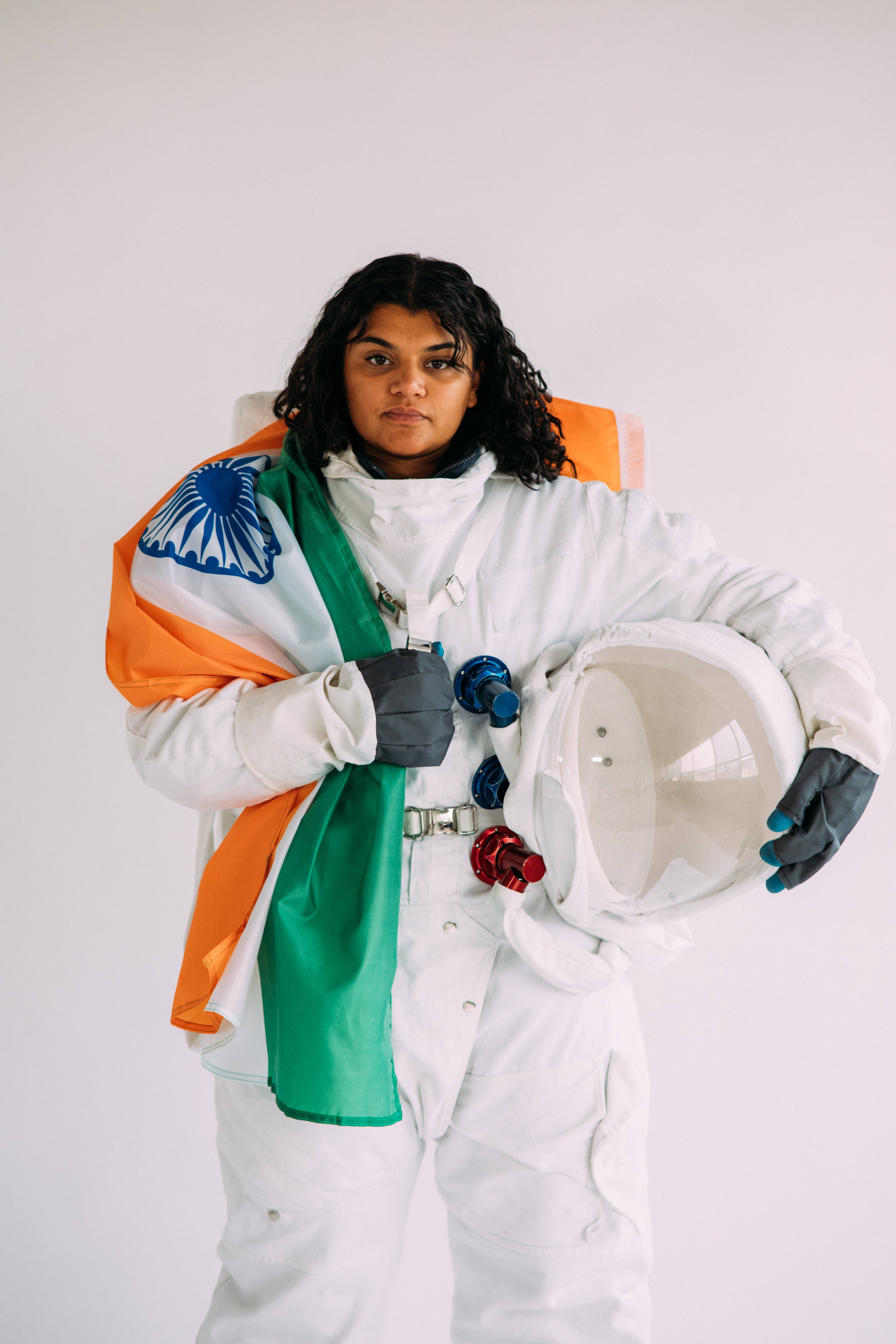 Tiranga 桌布 壁紙 — 一個穿著白色太空衣的人，披著印度國旗，在純白色背景前拿著頭盔。