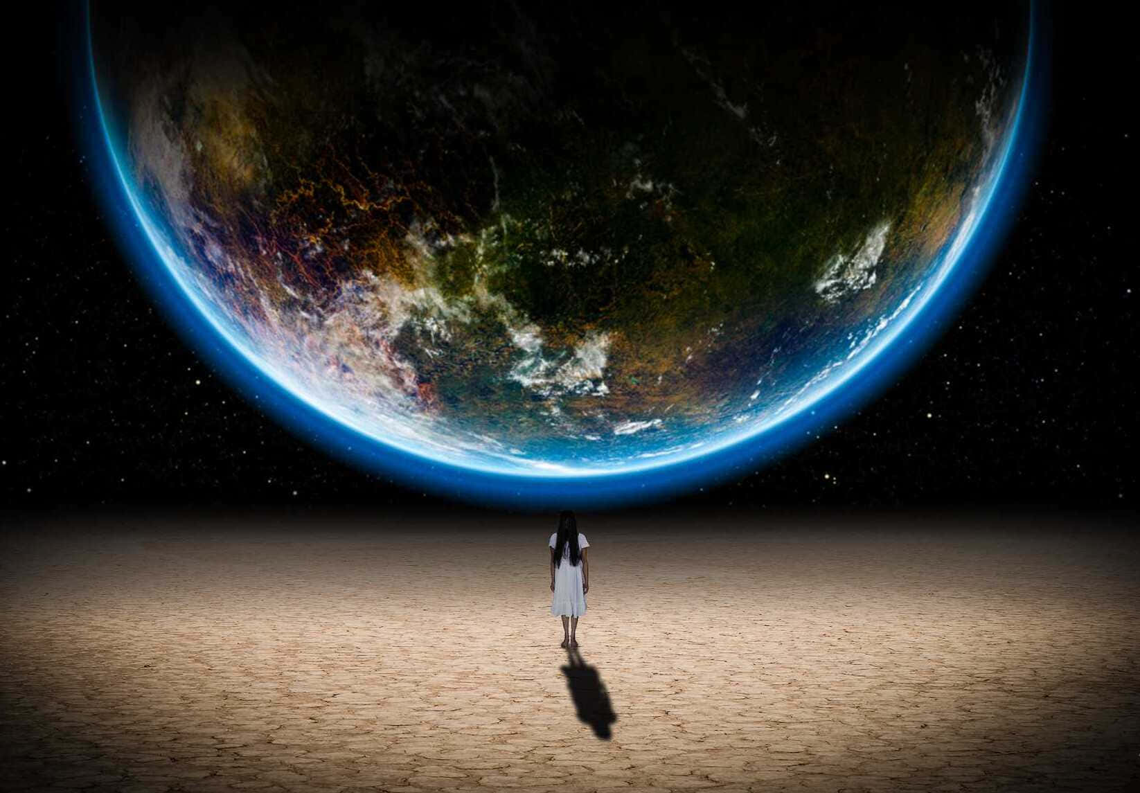 太空 桌布 壁紙 — 一個穿著白色連衣裙的孤獨身影站在荒蕪的星球上，仰望懸浮在星空中的巨大發光地球。