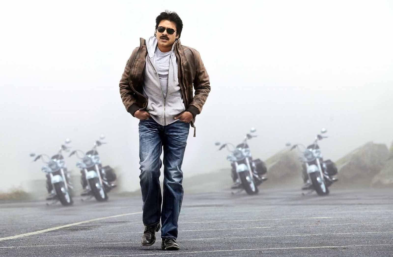 Pawan Kalyan 桌布 壁紙 — 一個穿著皮夾克和太陽眼鏡的男人自信地走在一條霧氣瀰漫的路上，身後排列著摩托車。