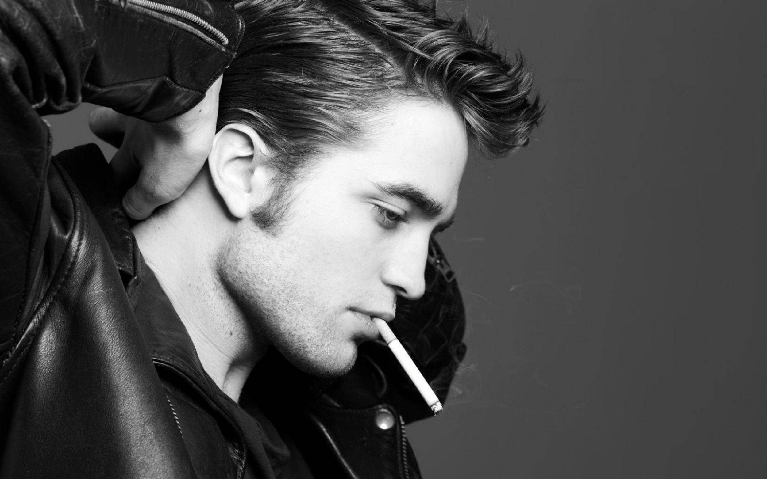 Robert Pattinson 桌布 壁紙 — 一個穿著皮夾克的男人，手放在脖子上抽煙的黑白肖像。