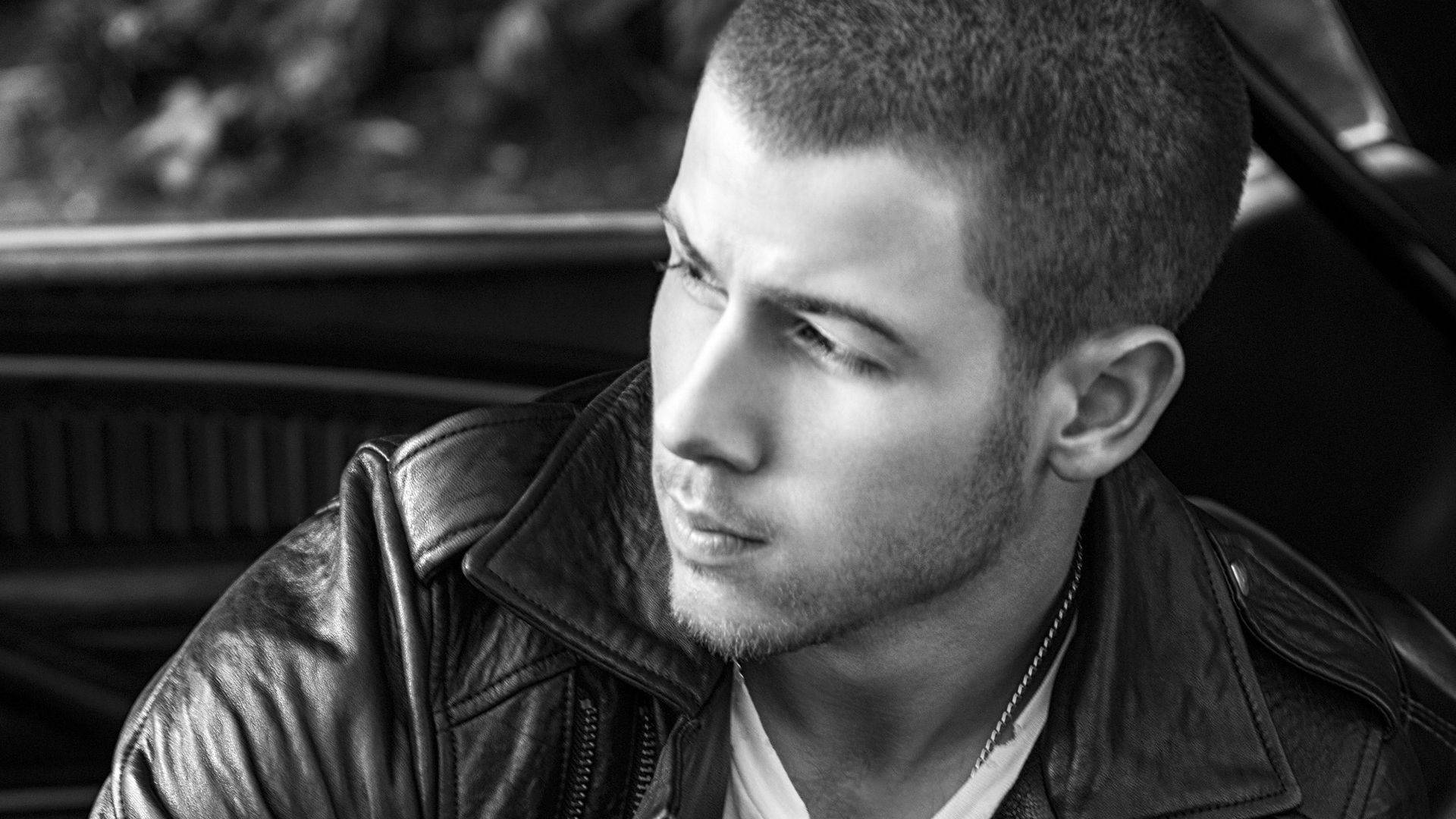 Nick Jonas 桌布 壁紙 — 一個穿著皮夾克的男人坐在車內，若有所思地望向一邊的黑白肖像。