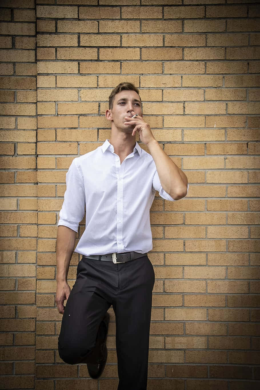 Man 桌布 壁紙 — 一個穿著筆挺白襯衫的男人靠著暖色調的磚牆抽煙。