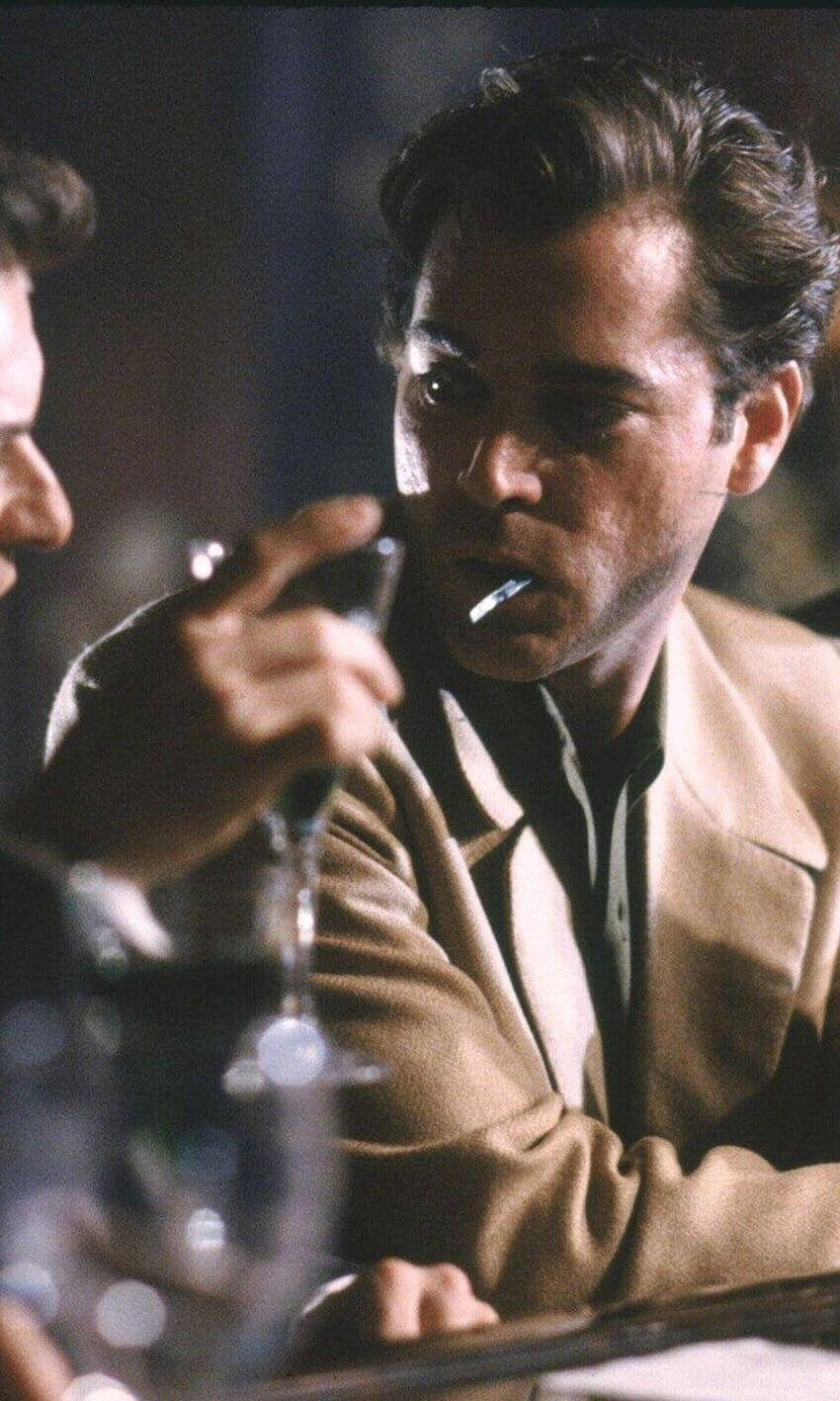 goodfellas 桌布 壁紙 — 一個穿著米色外套的男人在燈光昏暗的酒吧裡抽煙，手裡拿著酒杯。