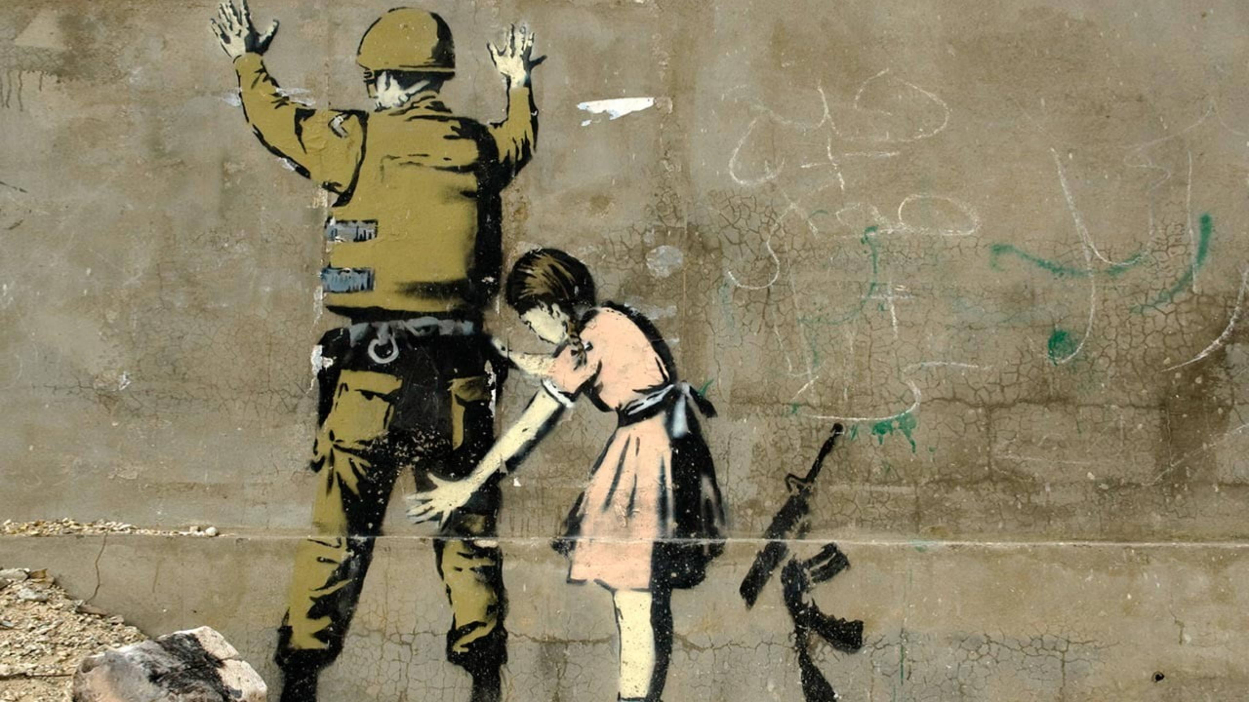 Banksy 桌布 壁紙 — 一個穿著粉紅色裙子的女孩輕輕觸摸一個士兵的手，他正舉起雙臂投降，背景是裂開的混凝土牆。
