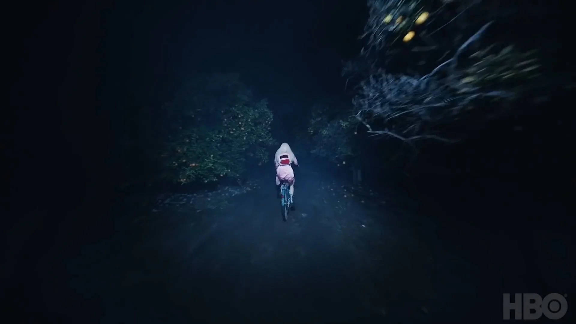 桌布 壁紙 — 一個穿著粉紅色連帽衫的小孩在夜晚沿著黑暗的森林小徑騎自行車，附近漂浮著發光的球體。