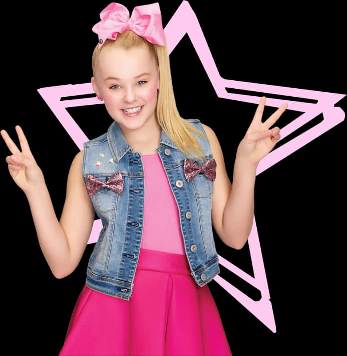 JoJo Siwa 桌布 壁紙 — 一個穿著粉紅色連衣裙和牛仔背心的開朗小女孩，在黑色背景上的粉紅色星星輪廓前微笑著做出和平手勢。