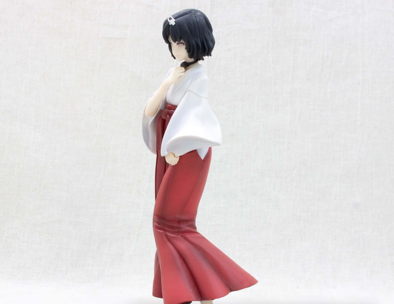 Luka Urushibara 桌布 壁紙 — 一個穿著紅白傳統服飾的動漫女角色人偶，站在樸素的紋理背景前。