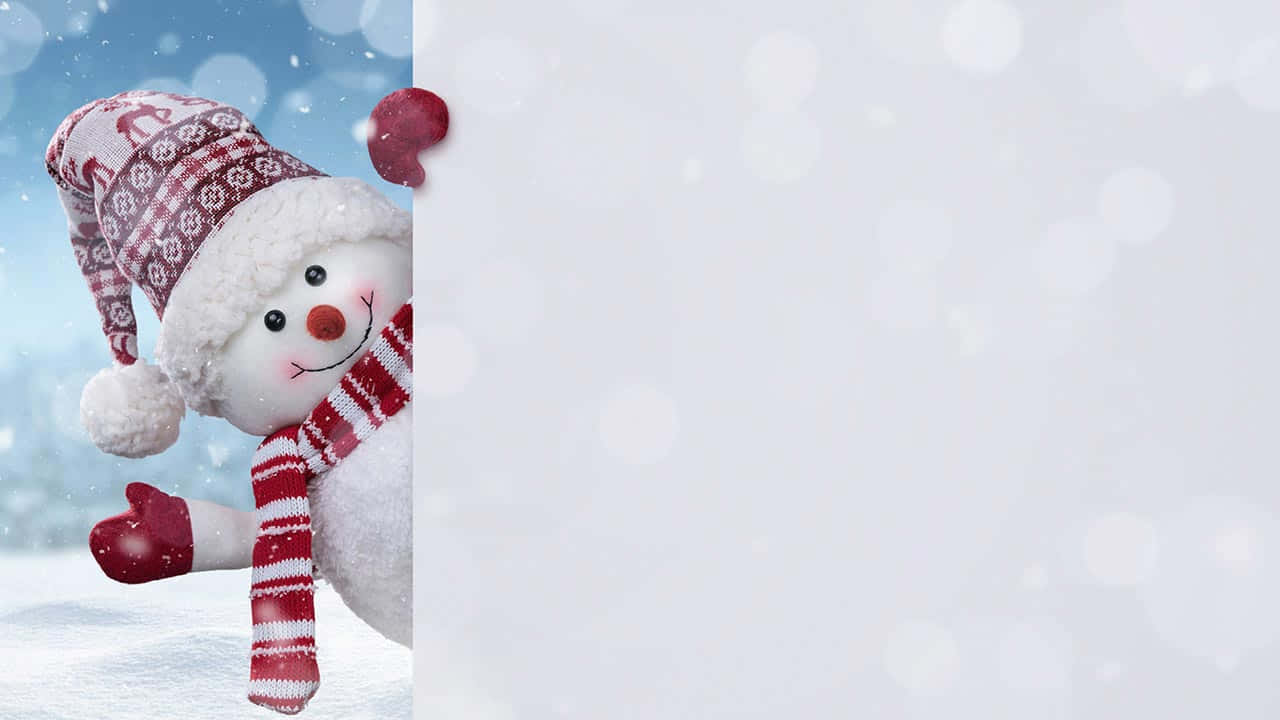  壁紙 — 一個穿著紅白冬季裝備的快樂雪人，從雪白面板後面窺視，背景是柔和的藍色冬日背景。