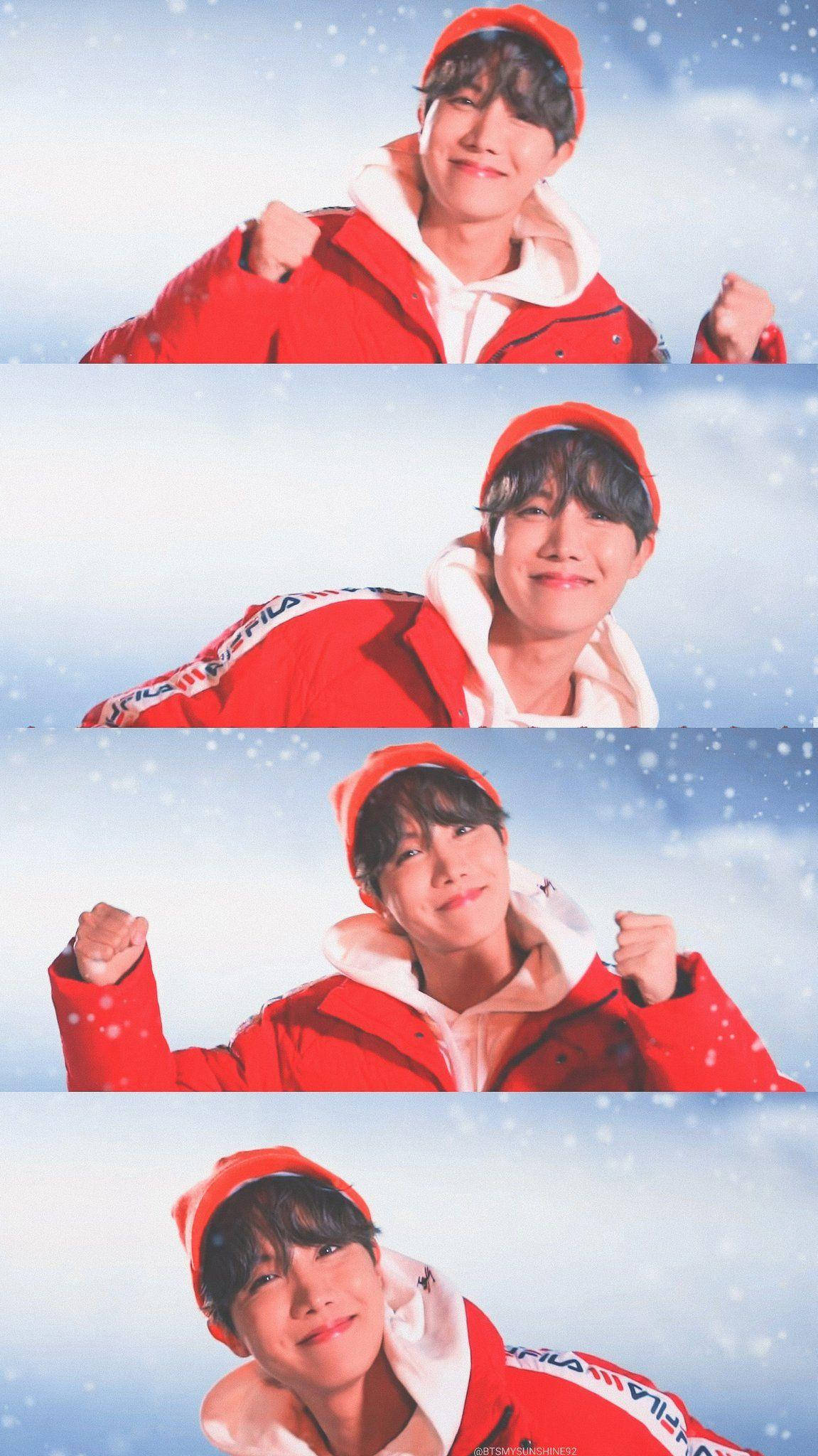 jhope 桌布 壁紙 — 一個穿著紅色冬季夾克和帽子的年輕男子，在雪景天空背景下自信地舉起拳頭擺姿勢。