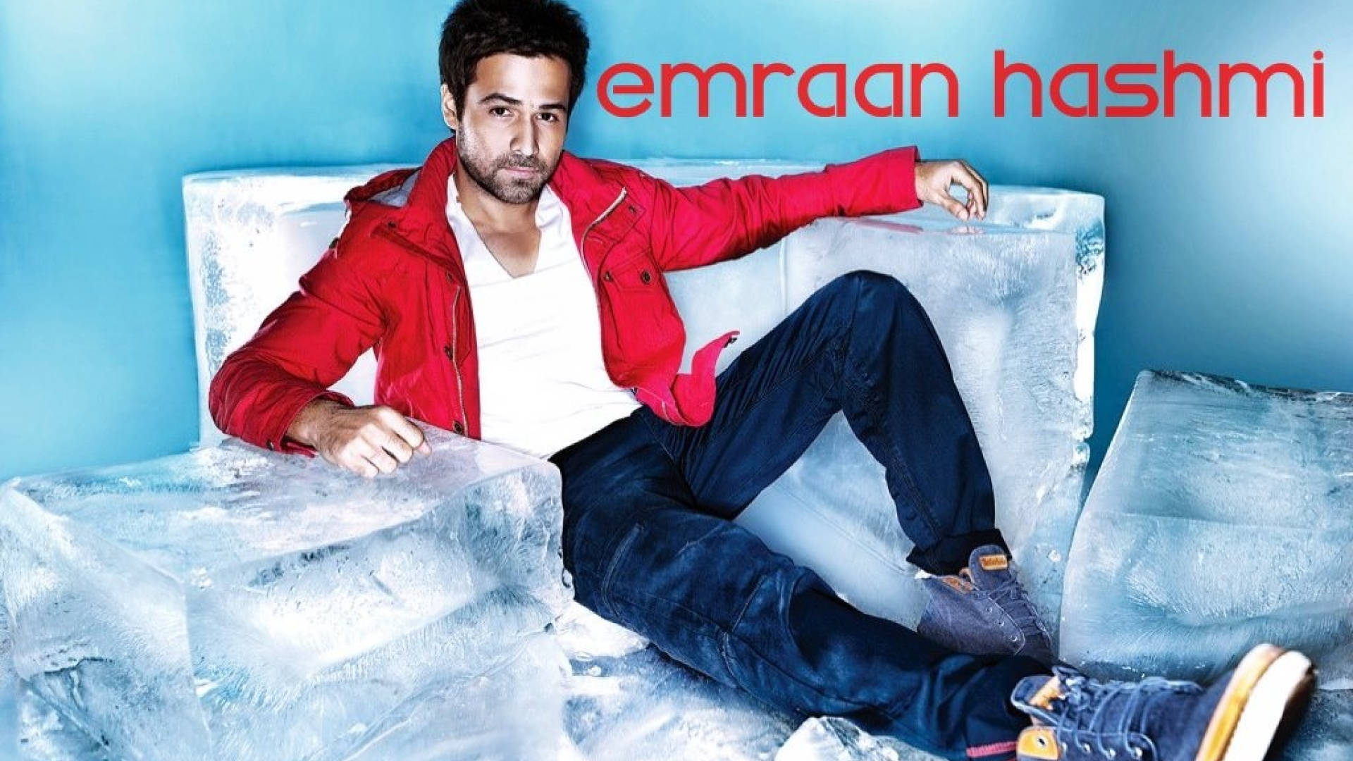 Emraan Hashmi 桌布 壁紙 — 一個穿著紅色外套的男人自信地躺在一塊巨大的冰塊上，背景是清涼的藍色牆壁，他的名字以紅色文字顯示。