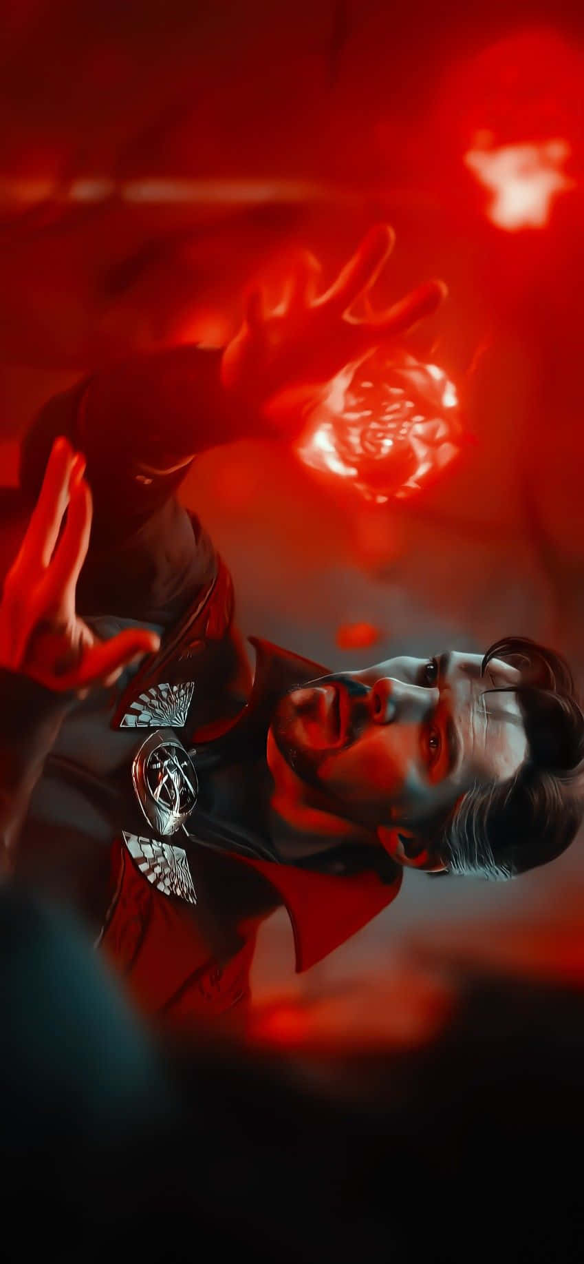 Doctor Strange Multiverse Of Madness 桌布 壁紙 — 一個穿著紅色斗篷的男人在深紅色背景前，透過雙手引導發光的紅色能量。
