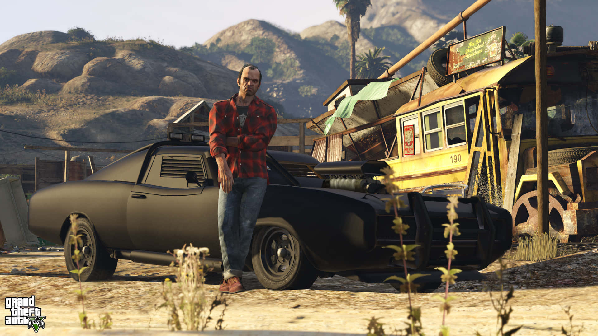 Grand Theft Auto V 桌布 壁紙 — 一個穿著紅色格子襯衫的男人，在塵土飛揚的沙漠廢車場，靠著一輛黑色肌肉車，背景有山。