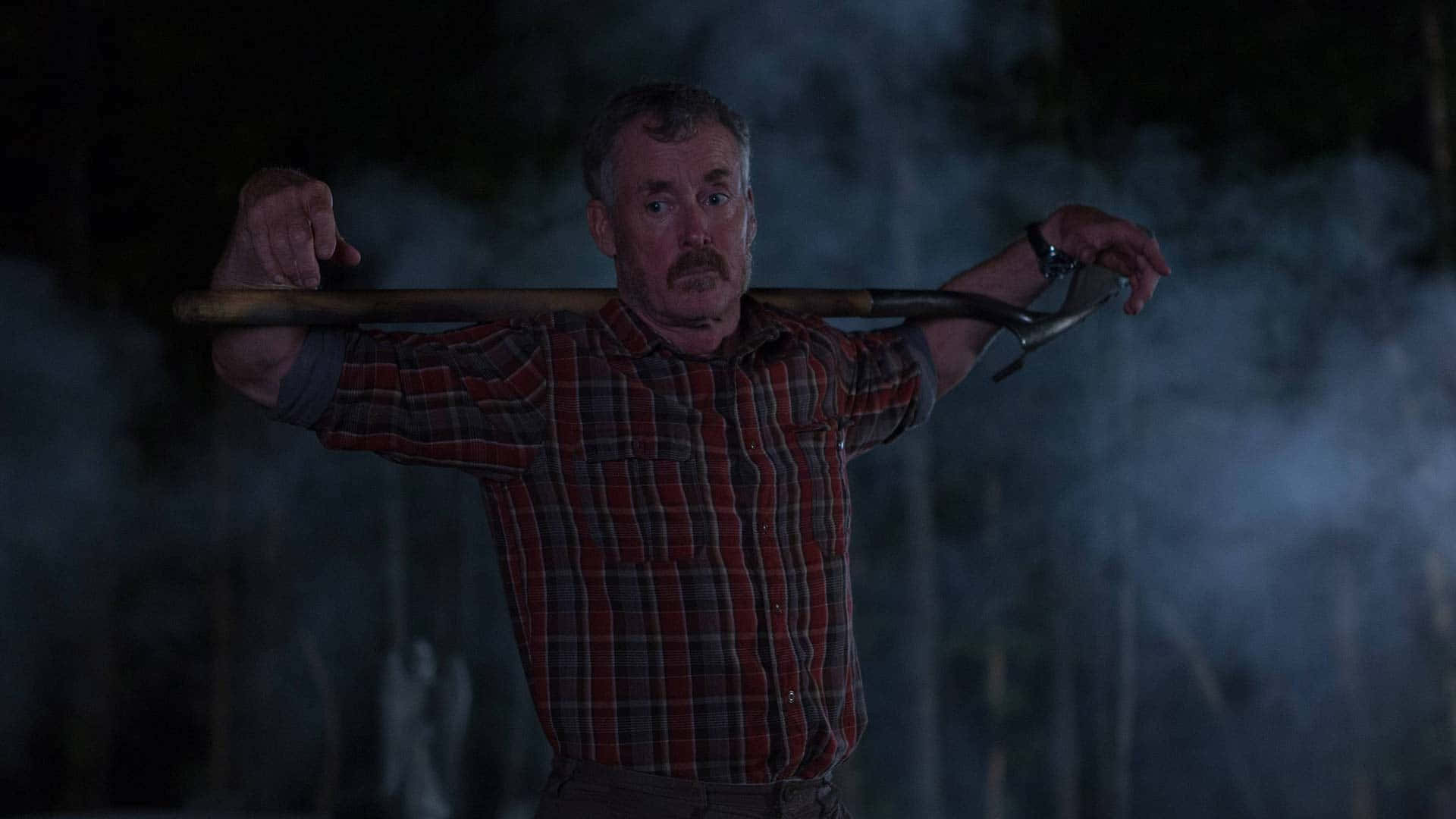John C. Mcginley 桌布 壁紙 — 一個穿著紅色格紋襯衫的男人在夜晚煙霧瀰漫的黑暗森林中將鏟子扛在肩膀上。