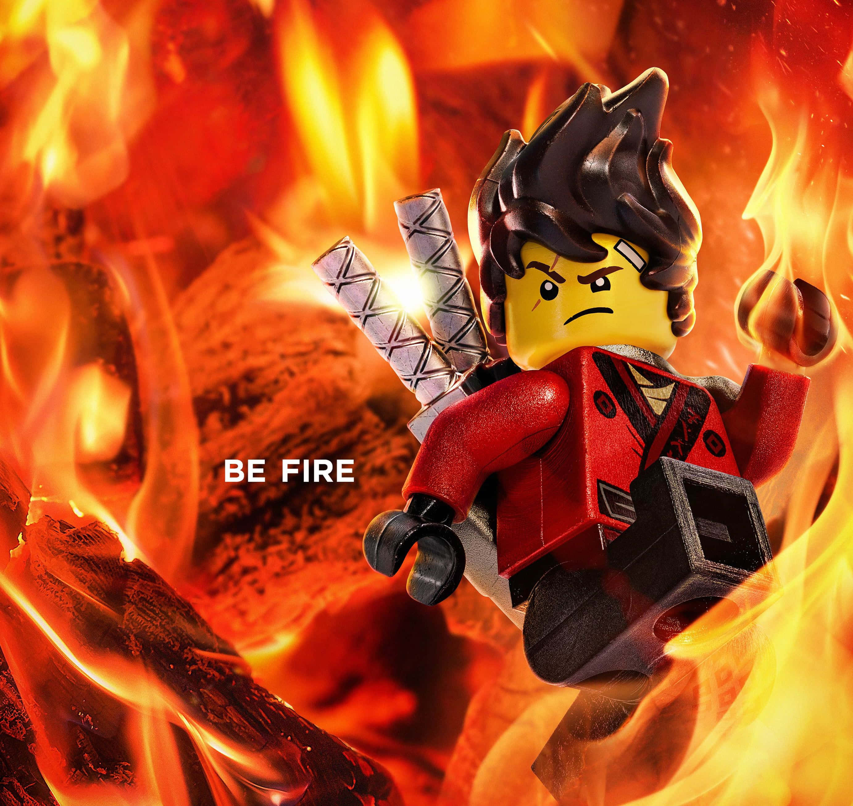Ninjago 桌布 壁紙 — 一個穿著紅色盔甲的LEGO忍者戰士，在咆哮的火焰中挑釁地站立，手持交叉的劍，並帶有文字BE FIRE。
