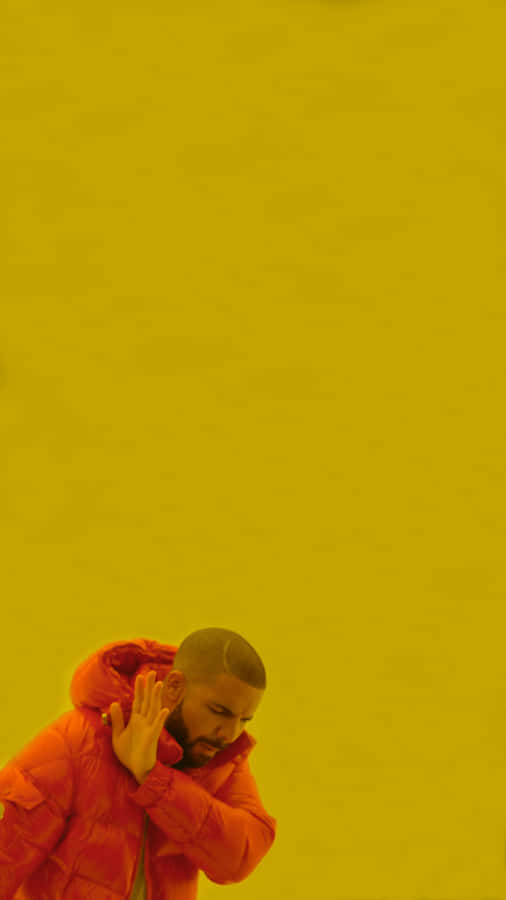 Aesthetic Drake 桌布 壁紙 — 一個穿著紅色羽絨外套的男人在純黃色背景前遮住耳朵。