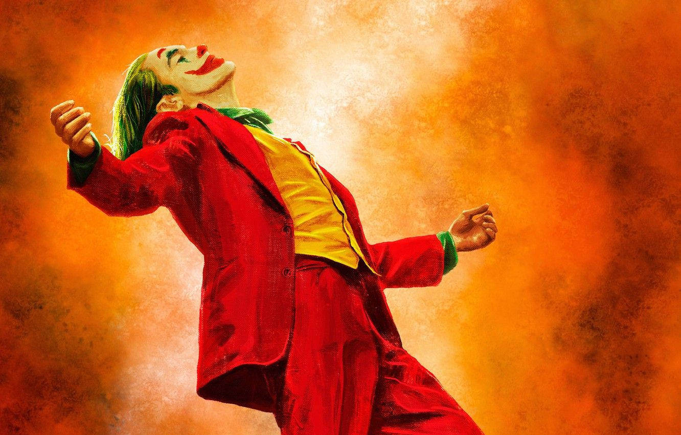Joker 2019 桌布 壁紙 — 一個穿著紅色西裝、綠色頭髮的男人在熾熱的橙色背景前狂笑。
