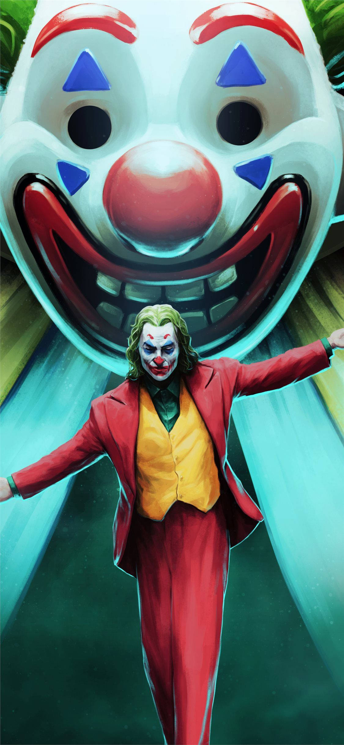 Joker 2019 桌布 壁紙 — 一個穿著紅色西裝的威脅性小丑站在一個巨大小丑面具前，面具露出寬闊的笑容，背景是發光的綠色。