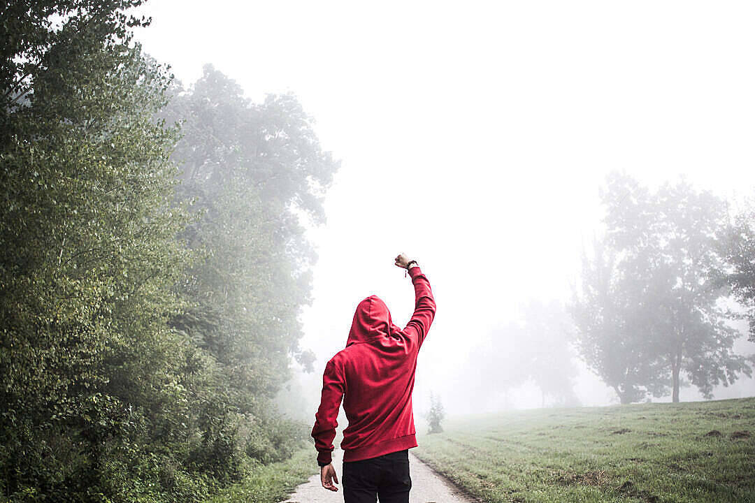 Motivation 桌布 壁紙 — 一個穿著紅色連帽衫的人，在森林小徑上行走時，向霧濛濛的天空舉起一隻手臂。