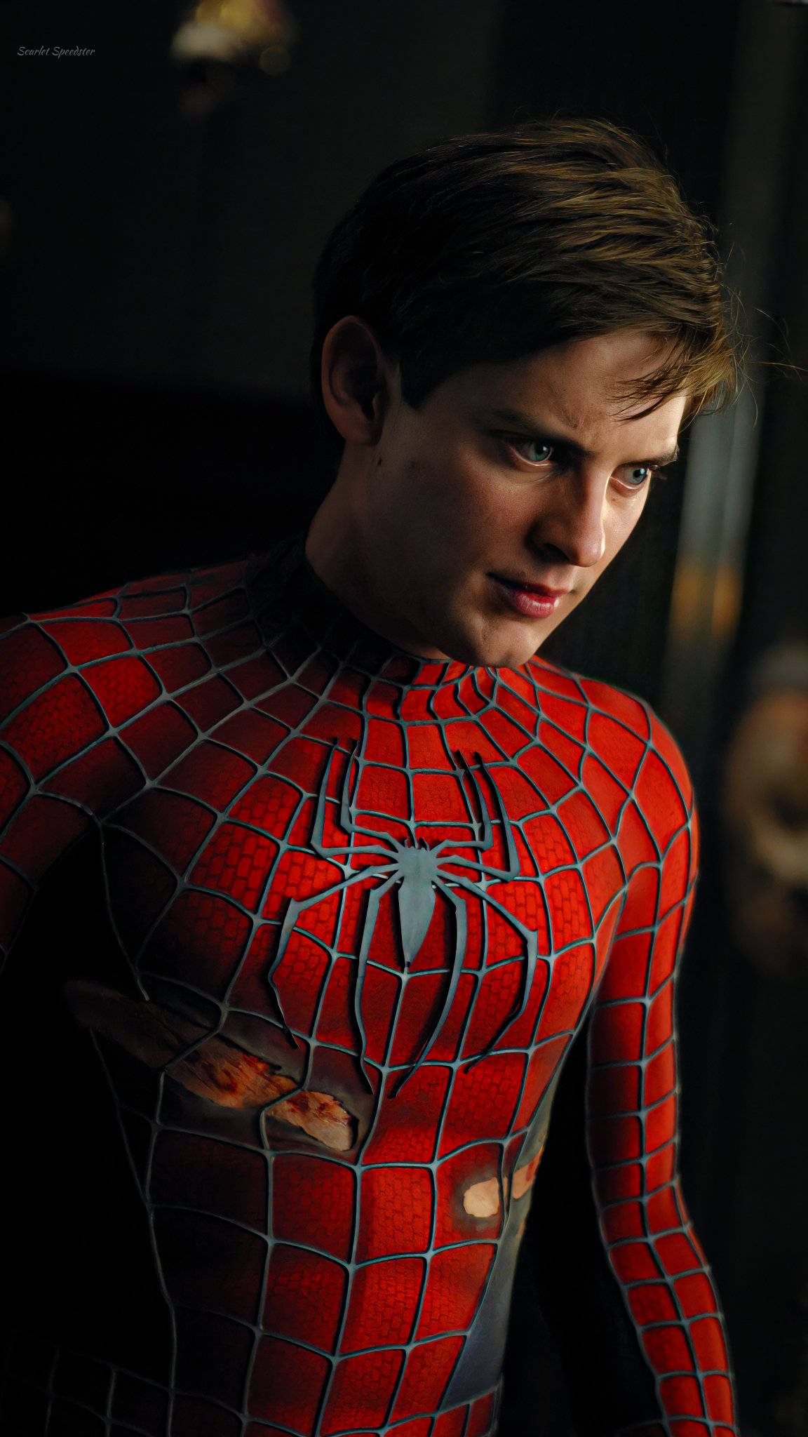 Spider Man 2 桌布 壁紙 — 一個穿著紅藍蜘蛛人戰衣、胸口面板破損的年輕男子，在昏暗的房間裡凝視著。
