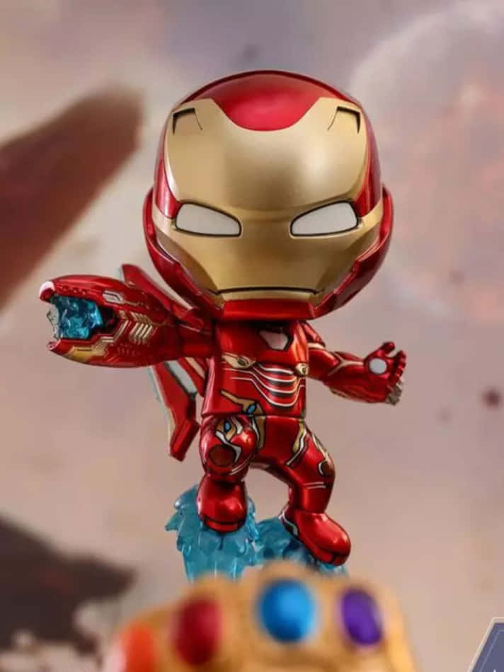 Iron Man Bobbleheads 桌布 壁紙 — 一個穿著紅金盔甲的Q版鋼鐵人人偶站在藍色能量底座上，前景是無限手套。