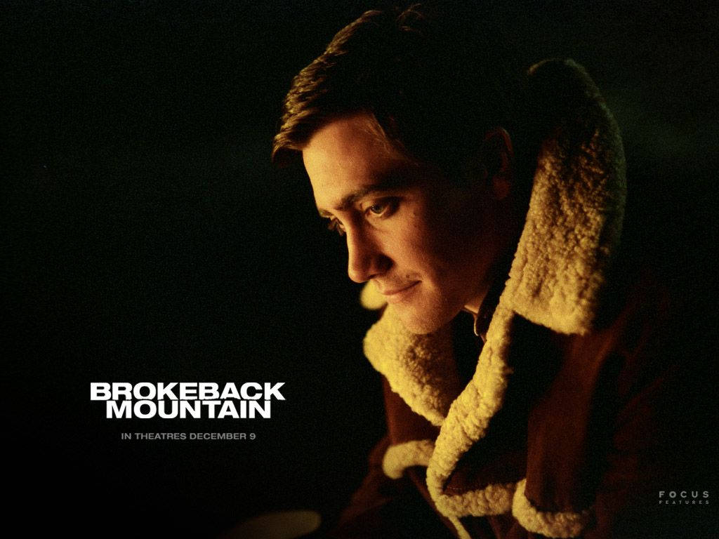 brokeback mountain 桌布 壁紙 — 一個穿著羊皮襯裡大衣的男人在昏暗的燈光下，對著黑色背景上的電影標題文字若有所思地凝視。