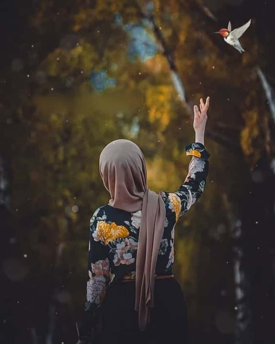 muslim 桌布 壁紙 — 一個穿著花卉上衣和希賈布的人向一隻在柔和模糊的秋林中飛翔的小鳥伸出手。