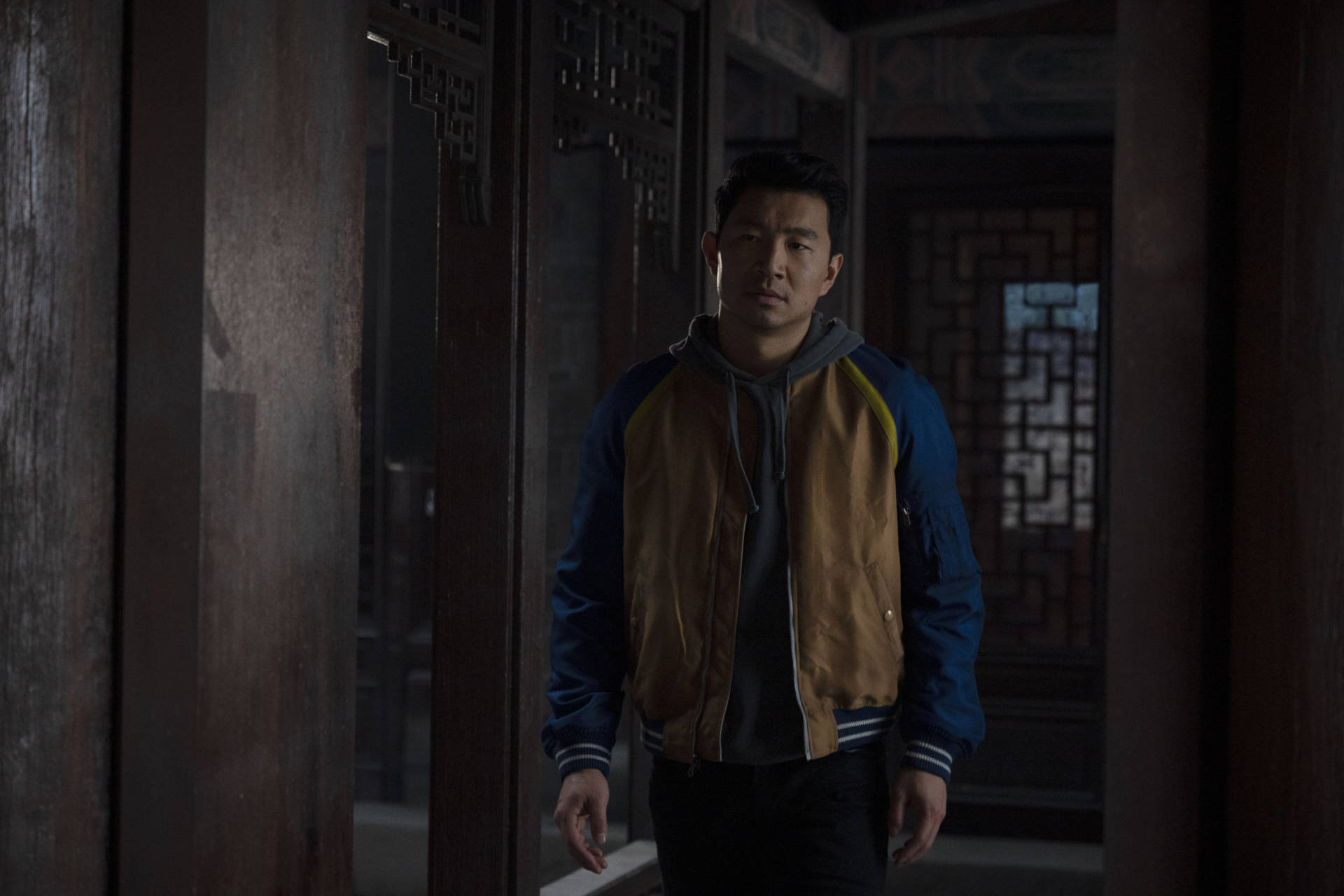 Shang 桌布 壁紙 — 一個穿著藍色和棕褐色外套的男人站在光線昏暗的傳統木製走廊中，走廊有精緻的格子窗。