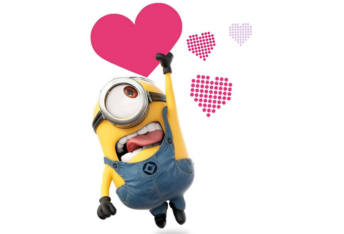 Minion 桌布 壁紙 — 一個穿著藍色工裝褲的快樂黃色小小兵，高興地抱著一個大粉紅心形，附近有較小的點點心形漂浮著。