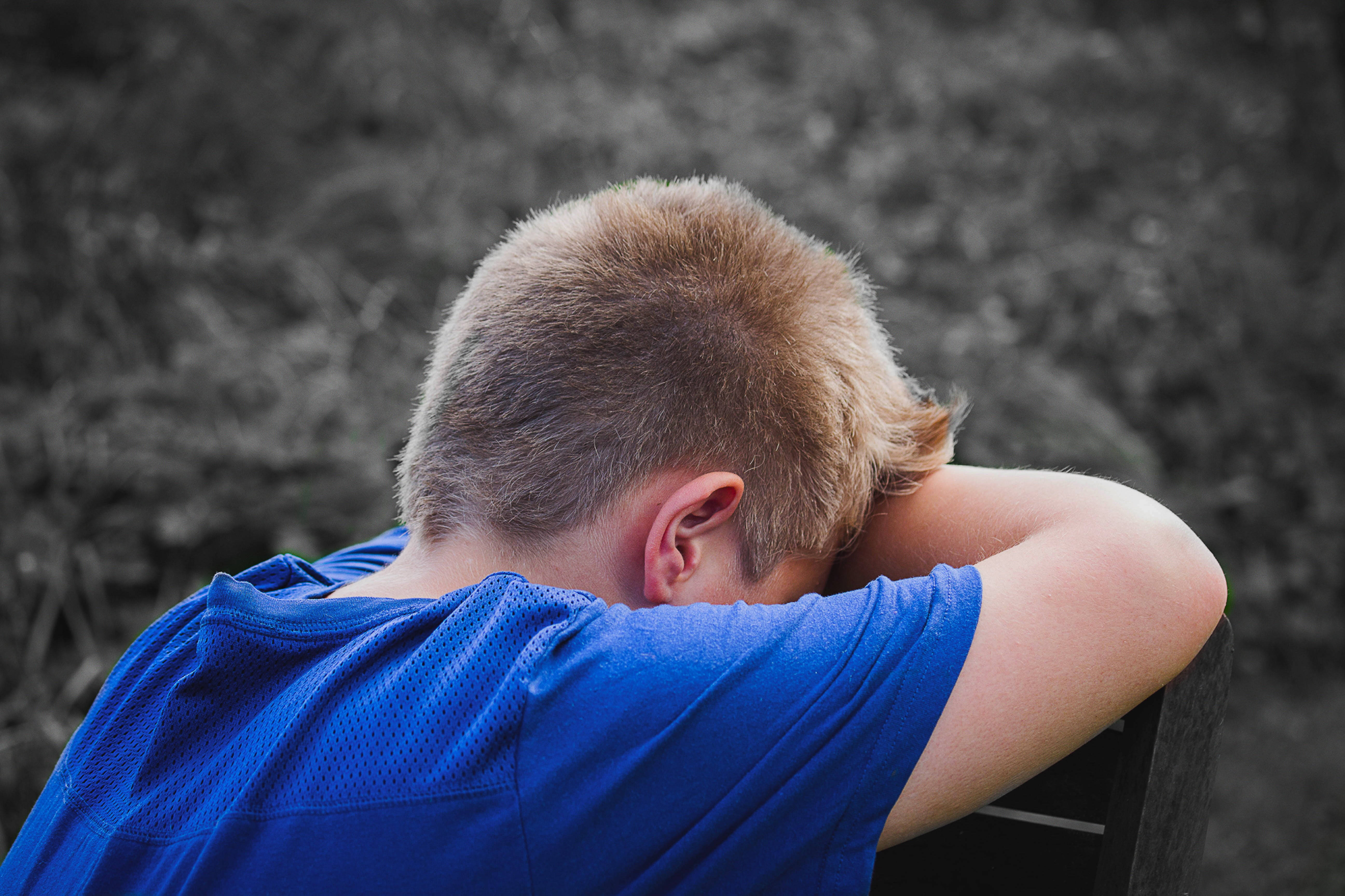 crying sad boy 桌布 壁紙 — 一個穿著藍色襯衫的小男孩坐在長椅上，頭靠在手臂上，背景是模糊的自然景色。
