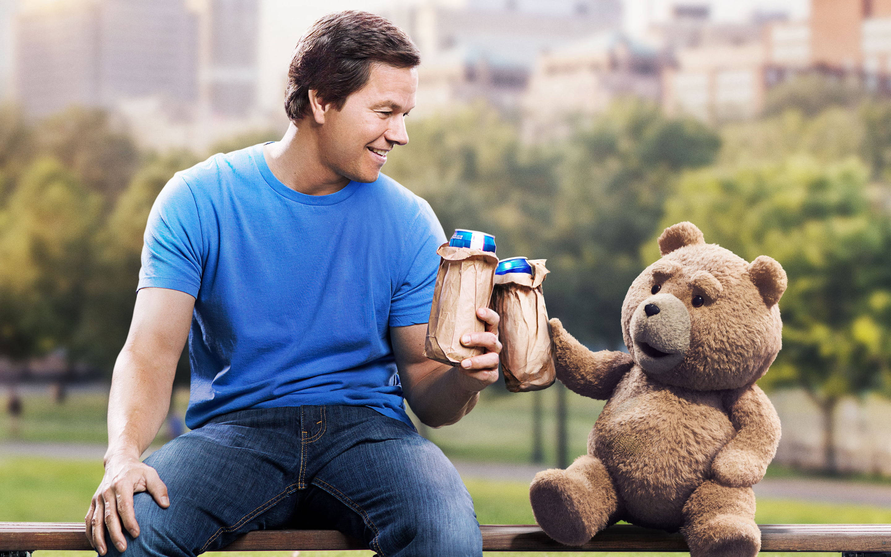 Ted 桌布 壁紙 — 一個穿著藍色襯衫的男人在柔和的日光下，與一隻會說話的泰迪熊在公園長椅上乾杯。