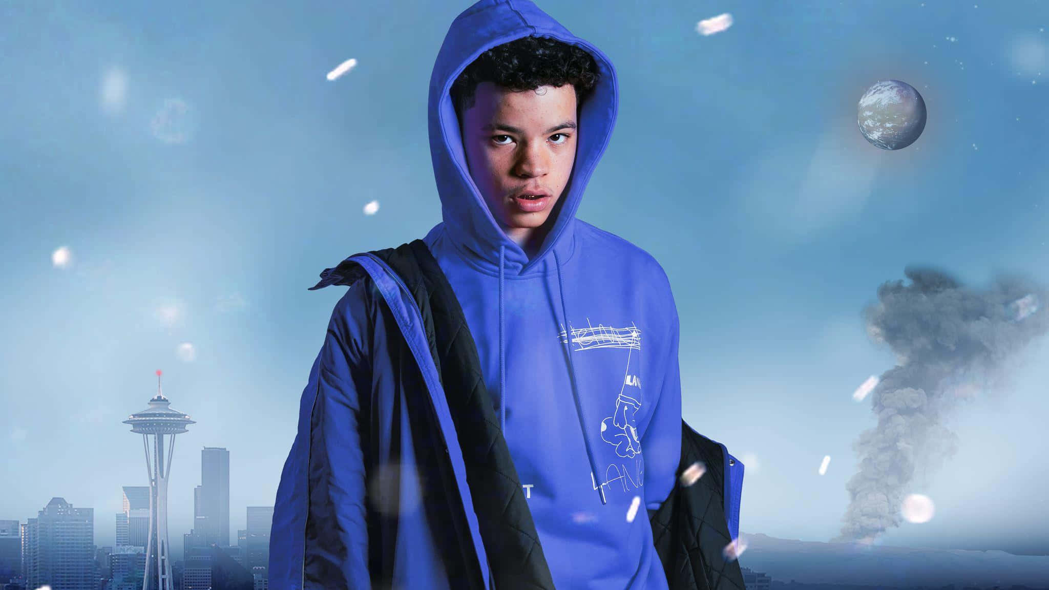 Lil Mosey 桌布 壁紙 — 一個穿著藍色連帽衫的年輕人站在超現實的西雅圖天際線前，有漂浮的月亮和煙霧柱。