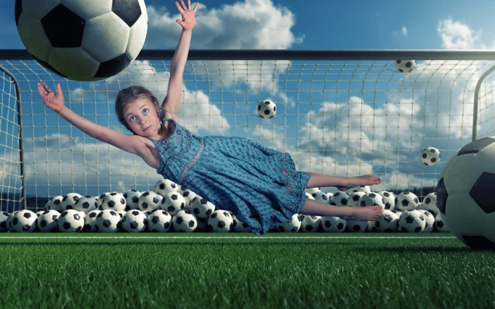 Funny Fantasy Football 桌布 壁紙 — 一個穿著藍色連衣裙的小女孩戲劇性地穿過一個足球球門網，周圍漂浮和堆積著足球，背景是明亮的藍天。