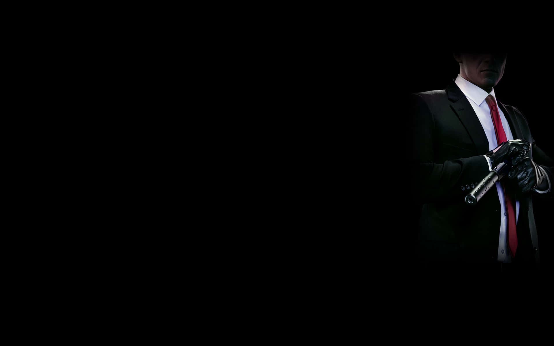 Hitman Desktop 桌布 壁紙 — 一個穿著西裝和紅色領帶的神秘身影，在戲劇性燈光下，手持槍枝對著黑色背景。