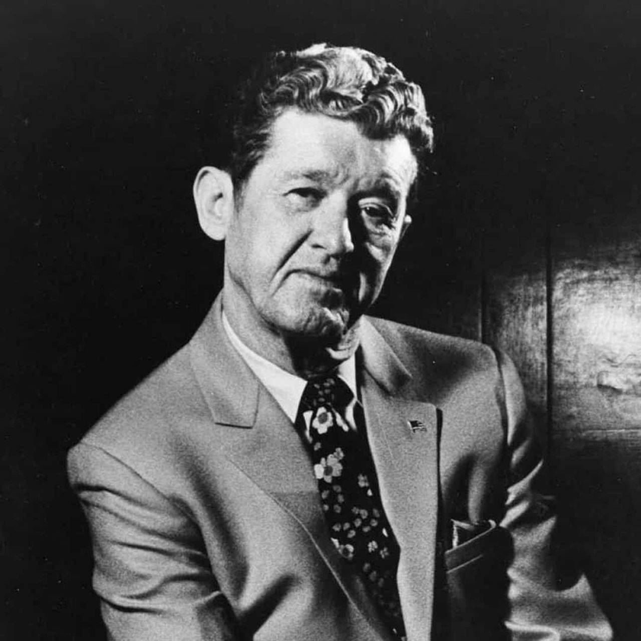 Singer 桌布 壁紙 — 一個穿著西裝和花卉領帶的男人在深色背景下的黑白肖像。