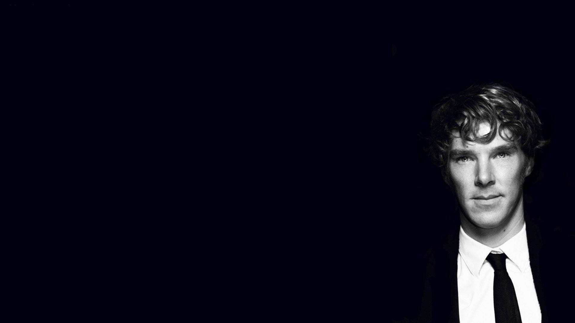 Sherlock Holmes 桌布 壁紙 — 一個穿著西裝打領帶的男人的黑白肖像，背景黑暗，燈光戲劇性。