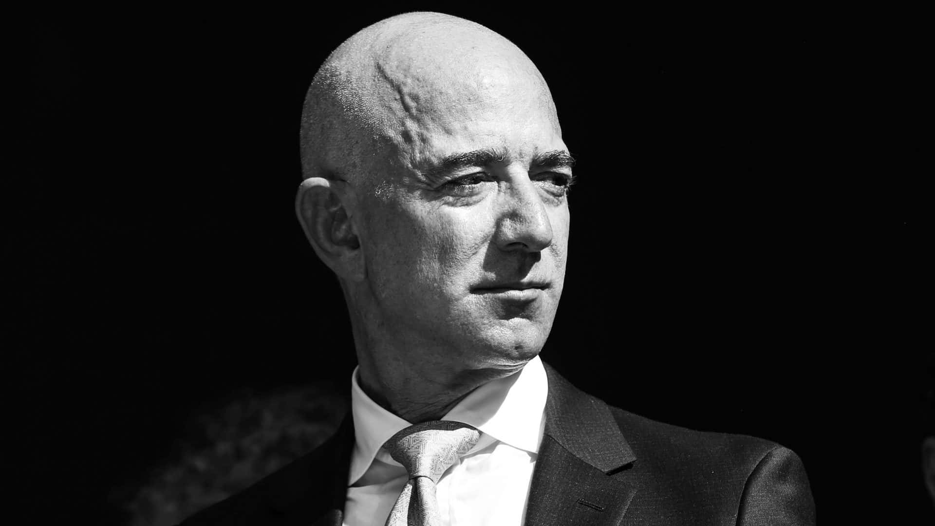 Jeff Bezos 桌布 壁紙 — 一個穿著西裝的光頭男人在黑暗背景下若有所思地望向一邊的黑白肖像。