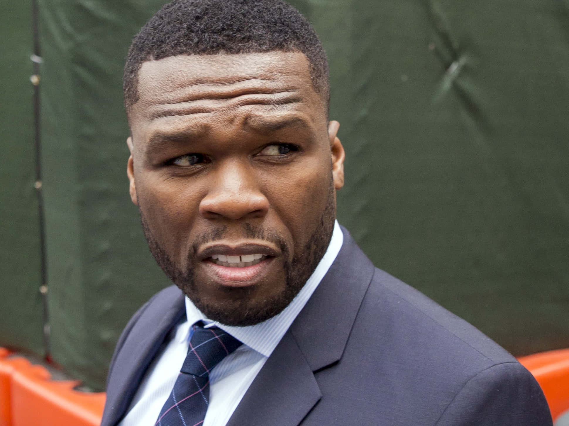 50 Cent 桌布 壁紙 — 一個穿著西裝的男人，眉頭緊鎖，表情嚴肅，以綠色背景為襯的特寫。