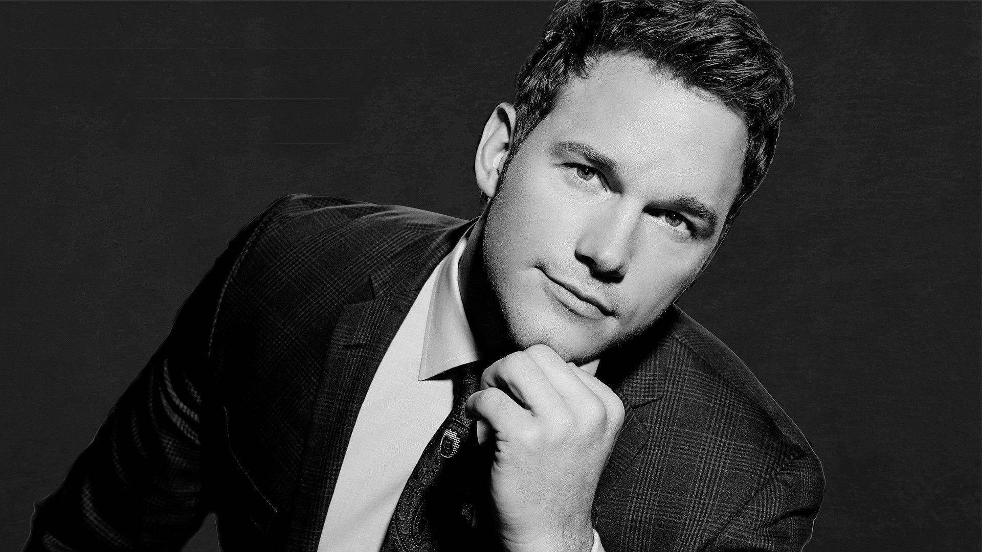 Chris Pratt 桌布 壁紙 — 一個穿著西裝的男人在深色背景下將下巴擱在手上的黑白肖像。