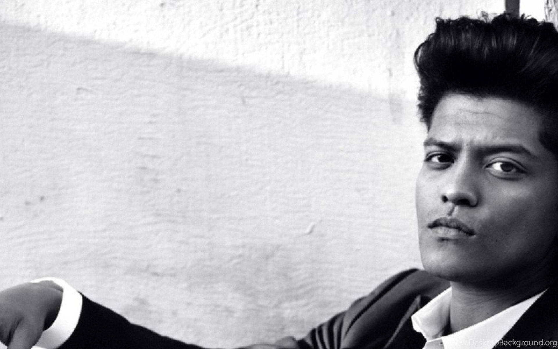 Bruno Mars 桌布 壁紙 — 一個穿著西裝的男人在紋理牆壁前專注地看著相機的黑白肖像。